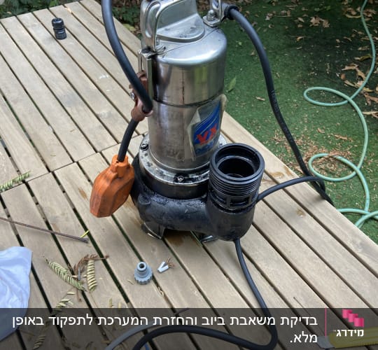 משאבה עם צינורות וכלי עבודה על שולחן עץ